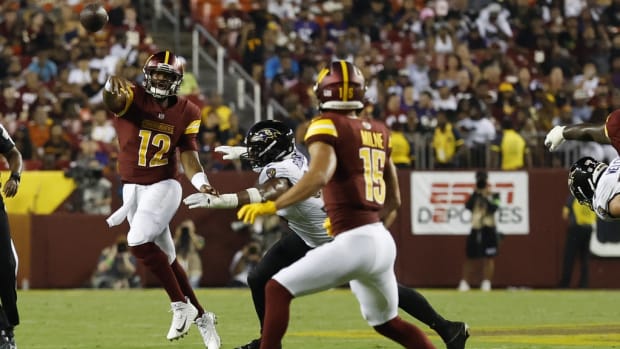 Washington Commanders quarterback Jacoby Brissett (12) passes the ball to Commanders wide receiver Dax Milne (15) as Baltimore Ravens linebacker Tavius Robinson (95) chases during the third quarter at FedExField.